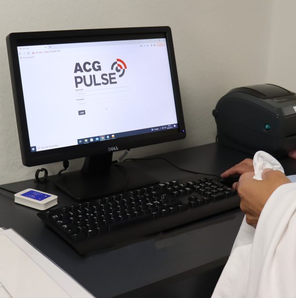 Computer screen showing ACG Pulse logotype. Registration station with rfid antenna under the desk